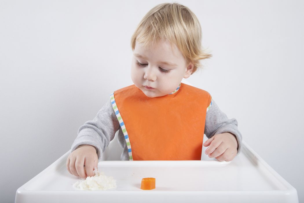 Baby isst Reis und Karotten
