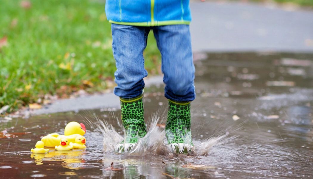 Kind springt bei Regen in die Pfütze reien bei Regen