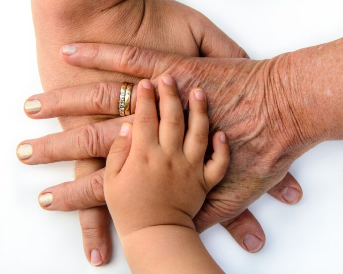 Hände dreier Generationen übereinander