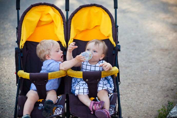 geschwisterwagen nebeneinander zwillinge sitzen zusammen im kinderwagen