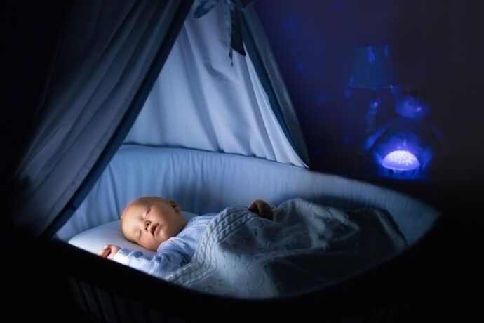 baby liegt mit eingeschaltetem nachtlicht schlafend im bett