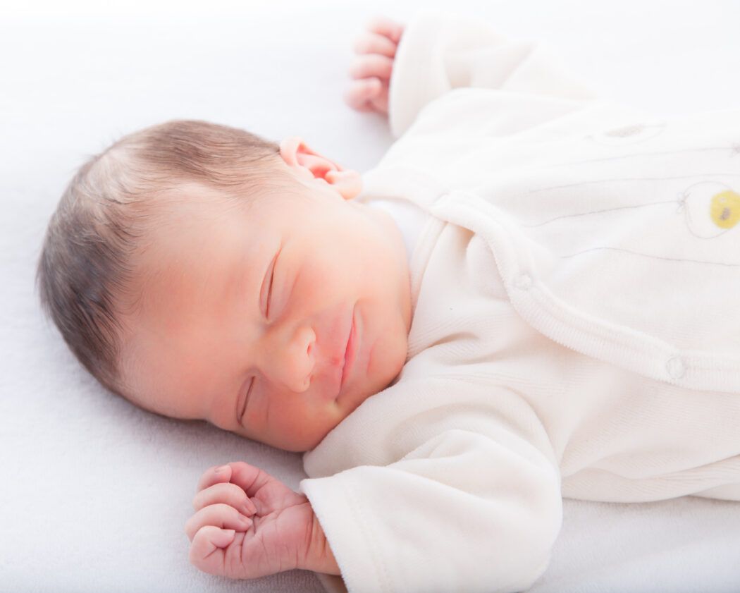wie finde ich den richtigen schlafsack fuer mein baby, baby laechelt schlafend im schlafsack