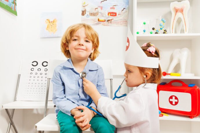 rollenspiele bei kindern kleines mädchen im arzt kostüm hört freund mit stethoskop ab