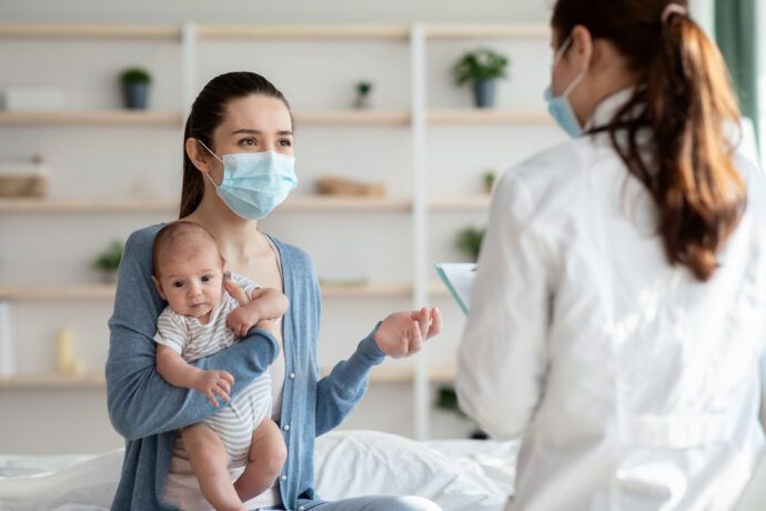 Corona Entwicklungsverzögernug Motorik Baby Entwicklung Studie, Mutter mit Maske beim Kinderarzt mit Baby