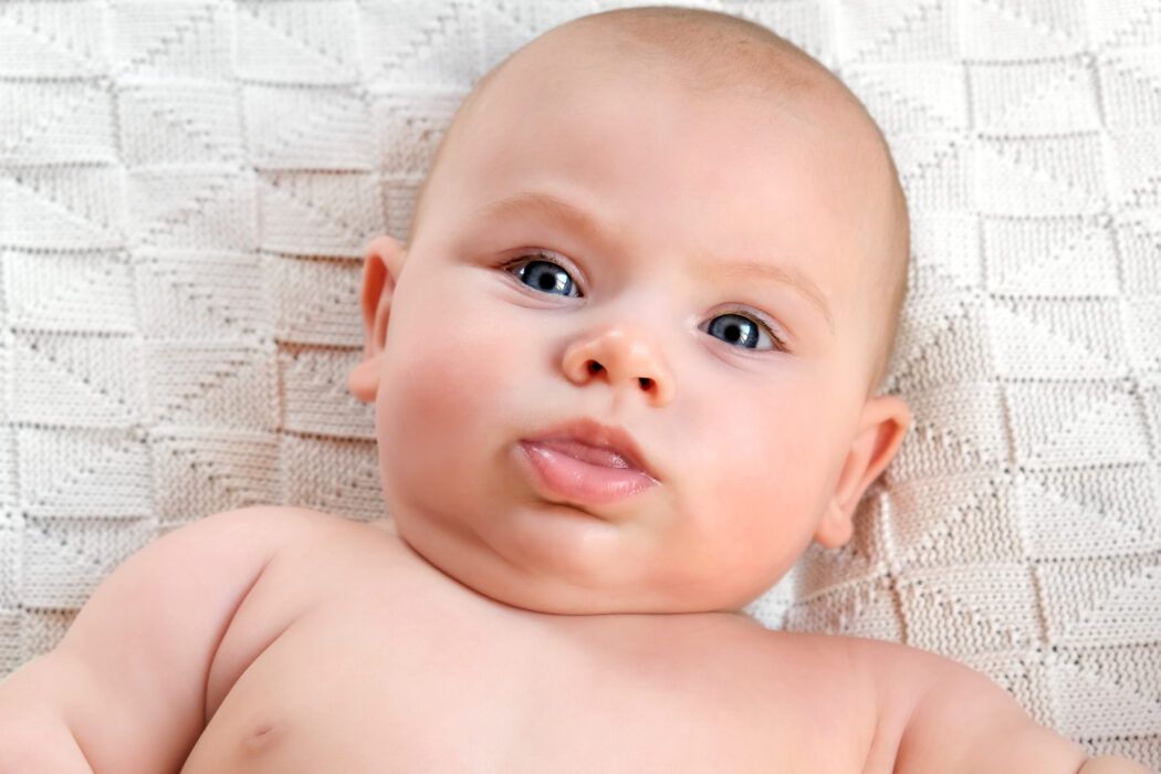 baby schaut unglücklich weil halsfalte wund und rot