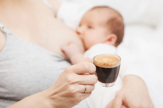 mutter trinkt kaffee und stillt dabei