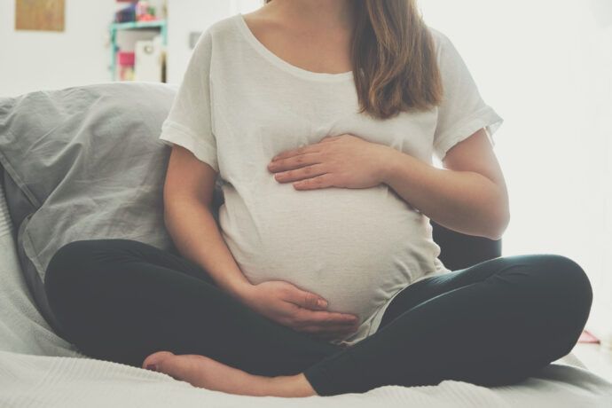 schwangere mit baby in querlage hält babybauch mit händen