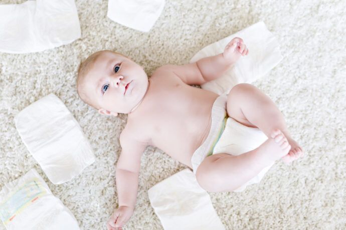 baby liegt zum windeln wechseln auf teppich