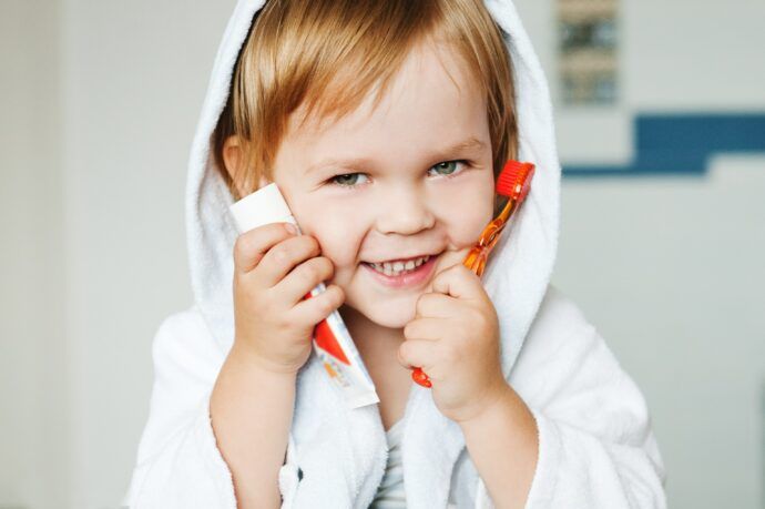 kinderzahnpasta test 2022 kleines mädchen lächelt und hält zahnpasta und zahncreme tube