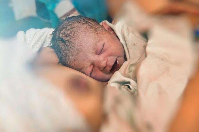 nach den phasen der geburt portrait neugeborenes baby auf brust der mutter im kreißsaal