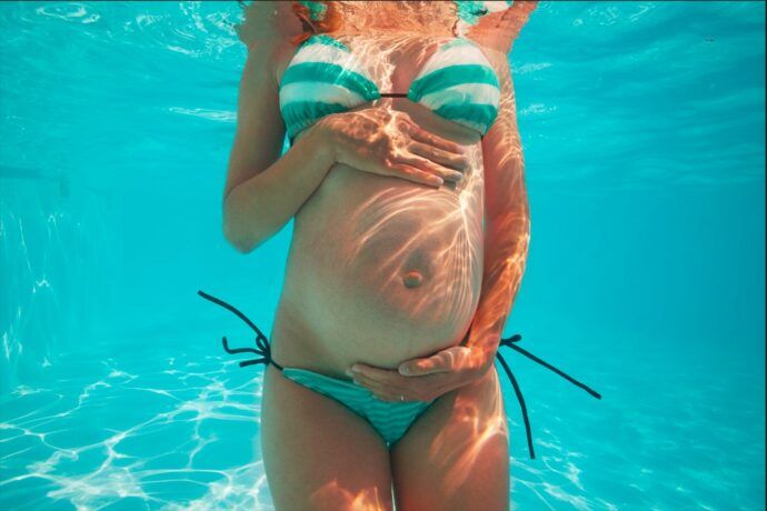 schwimmen in der schwangerschaft unter wasser bild frau hält babybauch mit den haenden