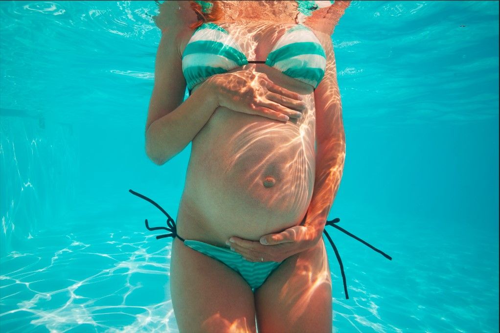 schwimmen in der schwangerschaft unter wasser bild frau hält babybauch mit den haenden