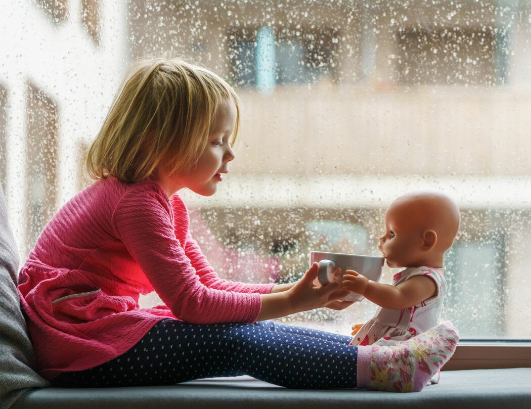 lagerkoller mit kindern, kind sitzt bei regenwetter auf der fensterbank