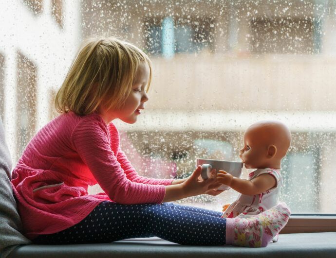 lagerkoller mit kindern, kind sitzt bei regenwetter auf der fensterbank