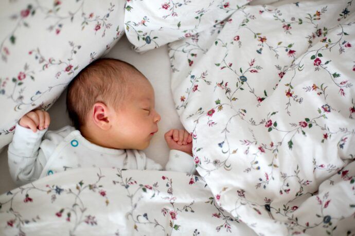plötzlicher kindstod sids als gefahr für schlafendes baby mit decke um den kopf