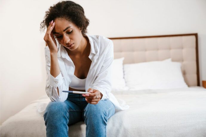Frau mit Schwangerschaftstest, ungeplant schwanger