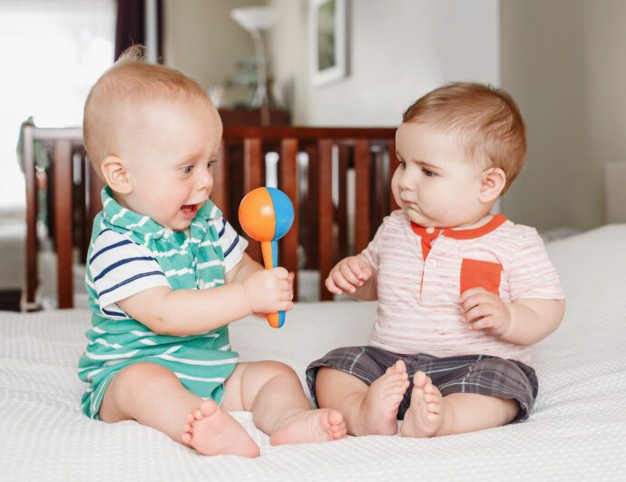 baby ist schwerhörig, zwei babys spielen mit einer rassel