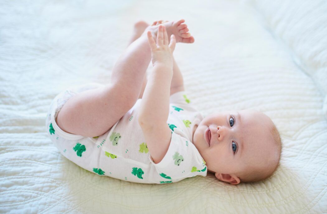 glückliches baby 6 monate alt liegt auf rücken greift füße