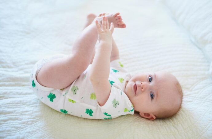 glückliches baby 6 monate alt liegt auf rücken greift füße