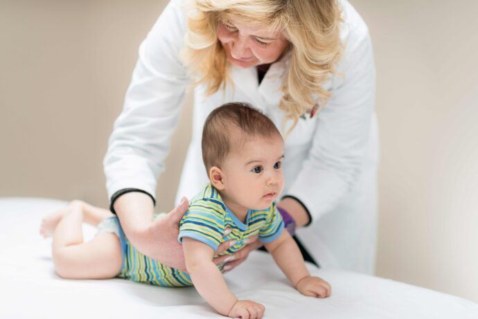 u5 untersuchung beim kinderarzt doktor hält 6 monate altes baby