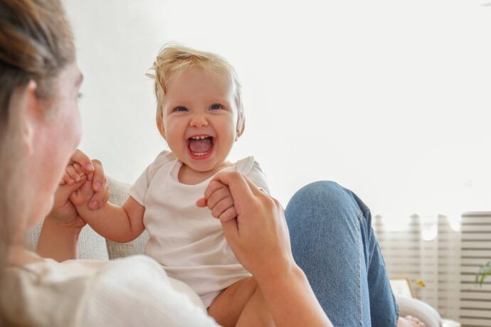 kniereiter spiel lachendes baby sitzt auf schoß der mutter