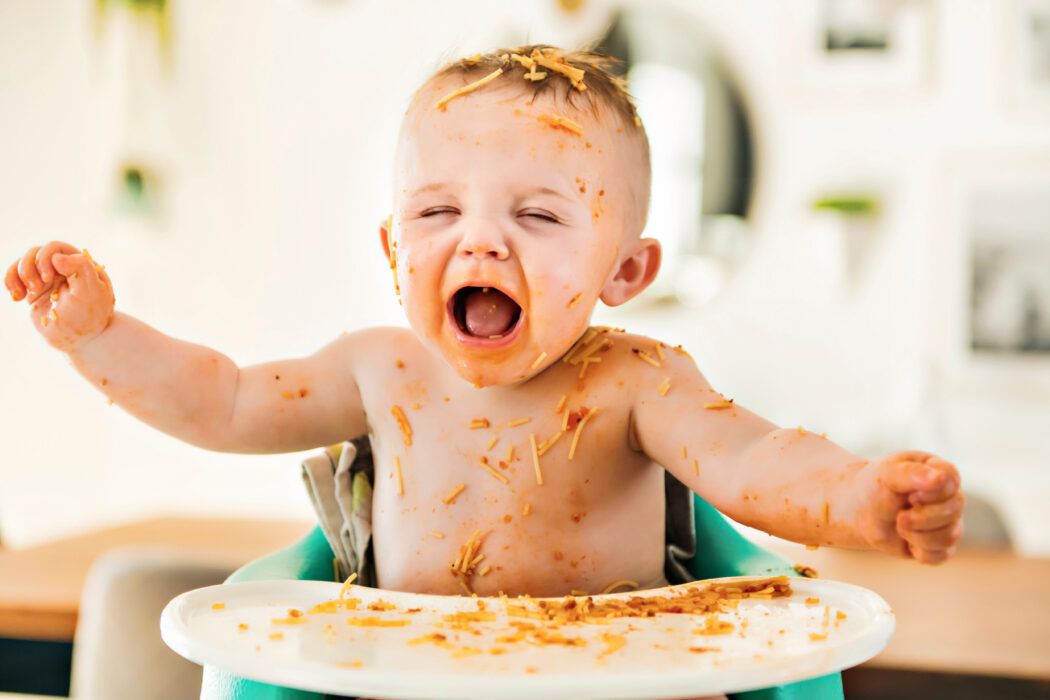baby im hochstuhl macht spaghetti schweinerei, baby macht sich beim essen schmutzig