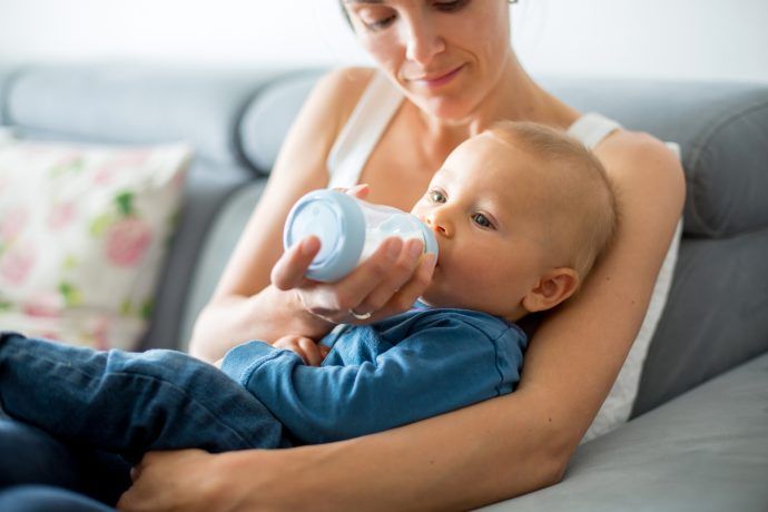 baby ist heiser trinkt milch aus flasche auf arm bei mutter