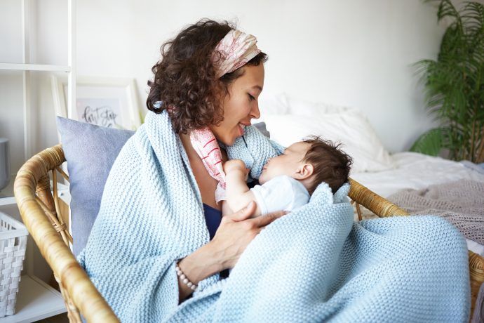 kranke mutter mit halsschmerzen in der stillzeit kuschelt mit baby eingehuellt in decke