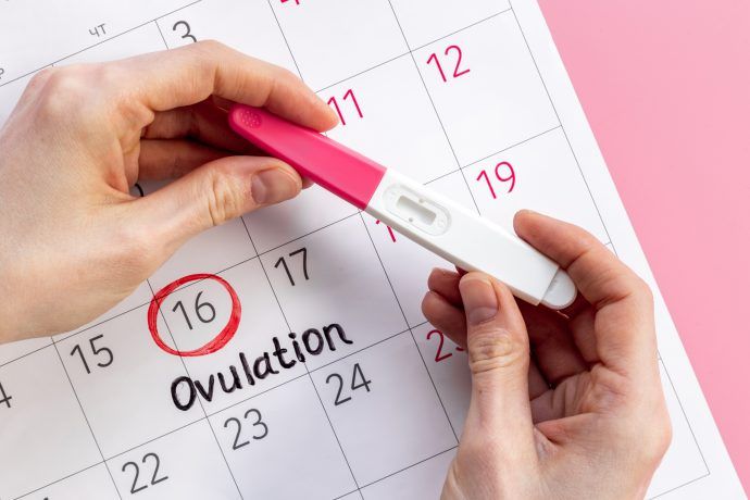 Frau hält Ovulationstest, Ovulationstest positiv wann Eisprung, wann GV