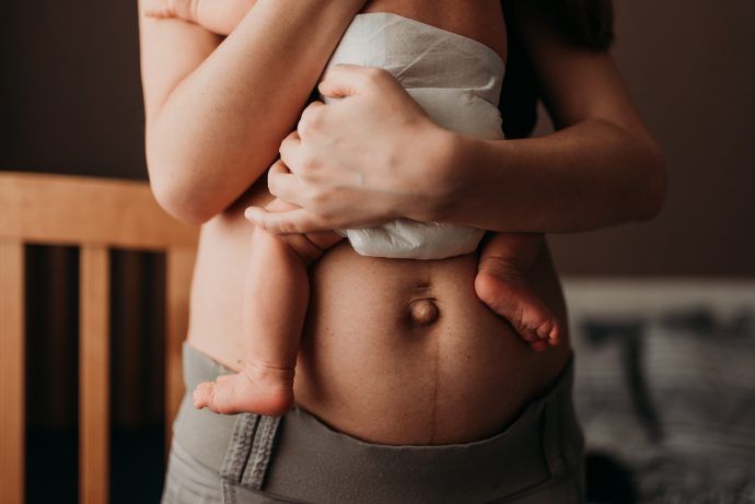 Bauch einer Mutter nach der Geburt mit Baby, Wochenflussstau Symptome