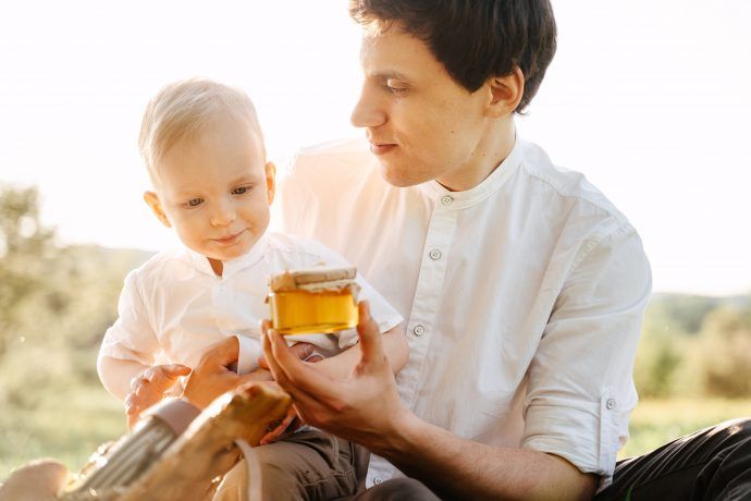 honig baby, vater und kind 12 monate alt bei picknick im freien mit honig glas