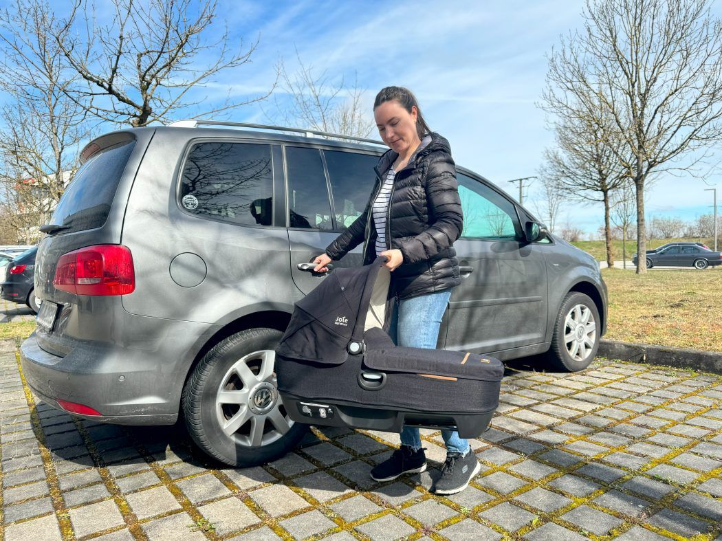 joie calmi person traegt babywanne zum auto