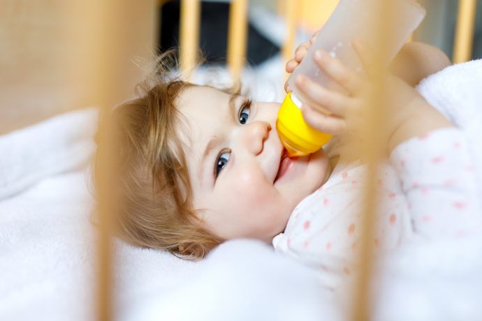 Kleinkind trinkt im Bett aus Milchflasche, Flasche nachts abgewöhnen ab wann