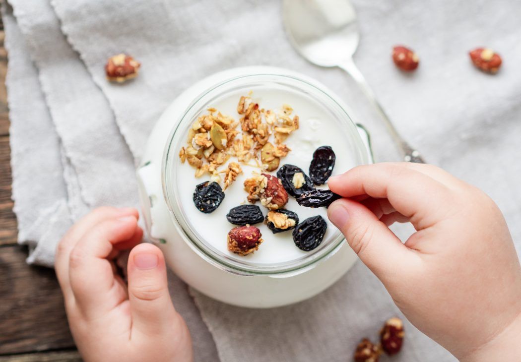 zangengriff, feinmotorik, kleinkind isst joghurt, greift rosine mit den fingerspitzen