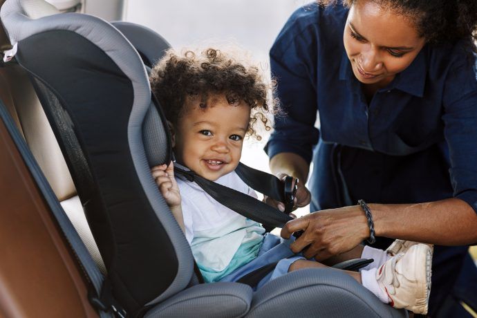 adac kindersitz test 2024 mutter schnallt kleinkind im kindersitz im auto an, sicherer kindersitz testsieger