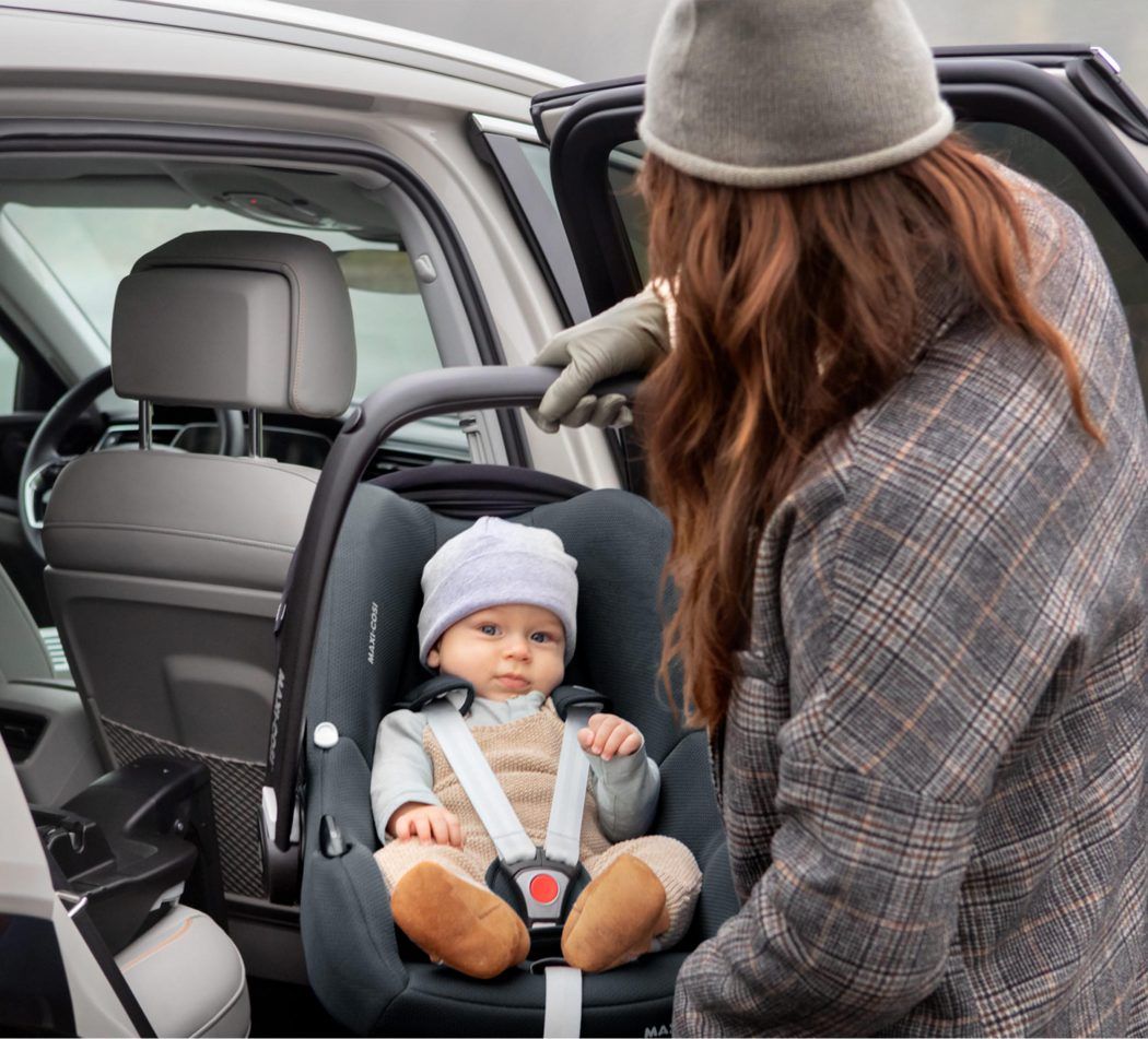 mutter traegt maxi cosi cabriofix i-size mit baby zum auto