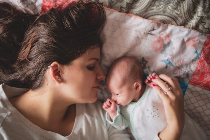 wochenbett mutter und neugeborenes baby liegen zusammen im bett kuscheln