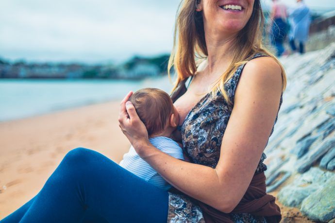 mutter und baby beim bergauf-stillen am strand