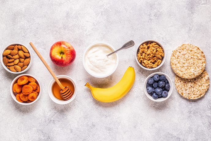 gesunde snacks schwangerschaft, schüsseln mit trockenfrüchten, joghurt, nüssen, obst, reiswaffeln, honig