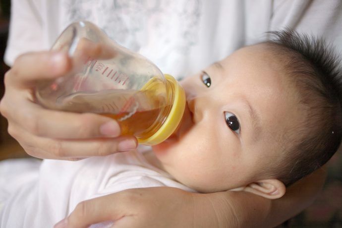 Baby trinkt Kamillentee aus einem Fläschchen, Kamillentee Baby