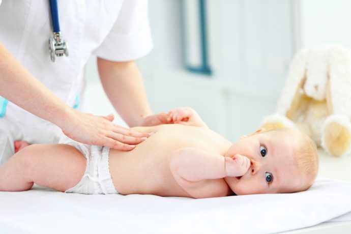 kinderarzt untersucht bauch eines babys, kuhmilchallergie baby symptome