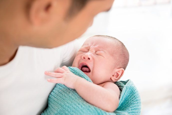 mundsoor baby weint im arm von vater