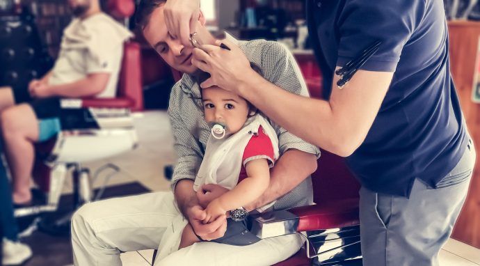 baby haare schneiden kleinkind mit schnuller auf papas schoß friseur erster haarschnitt