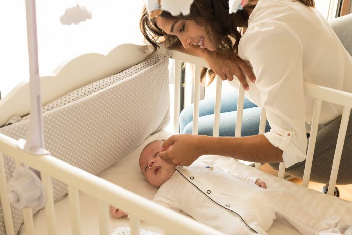 schlafbedarf baby mutter legt müdes baby zum mittagsschlaf in stubenwagen konzept babyschlaf