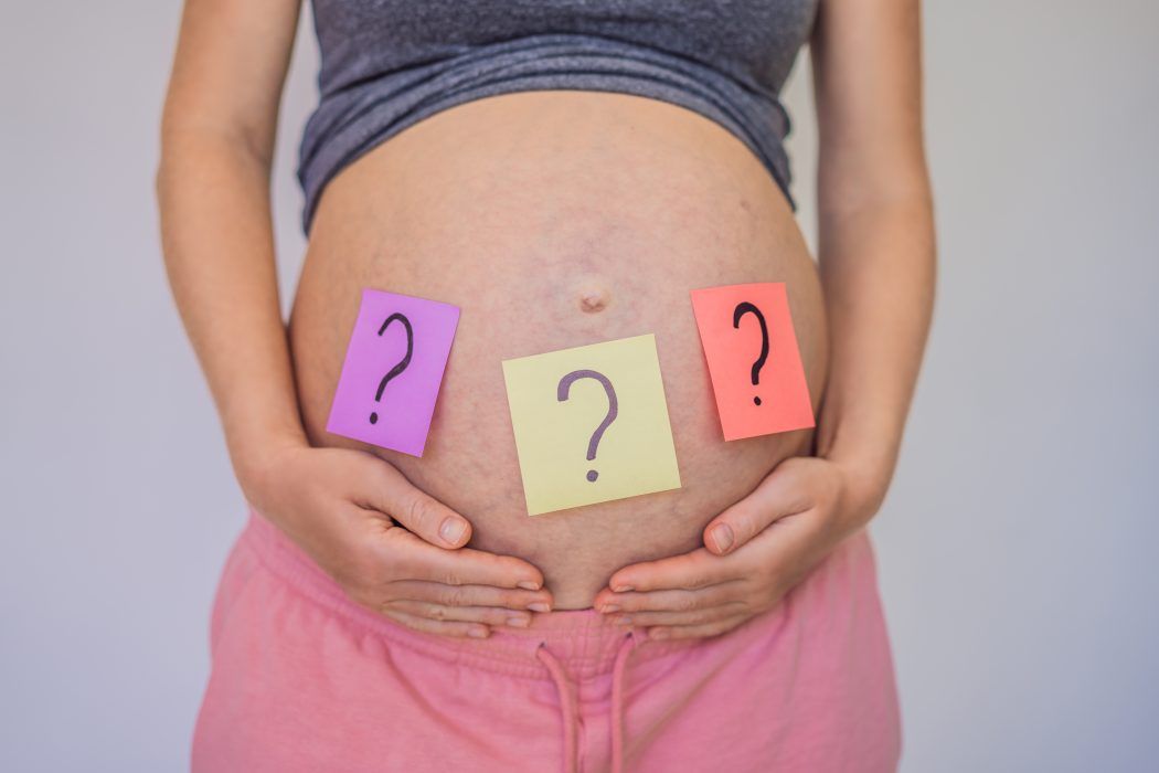 namenswahl babynamen 2024 babybauch schwangere frau notizzettel mit fragezeichen