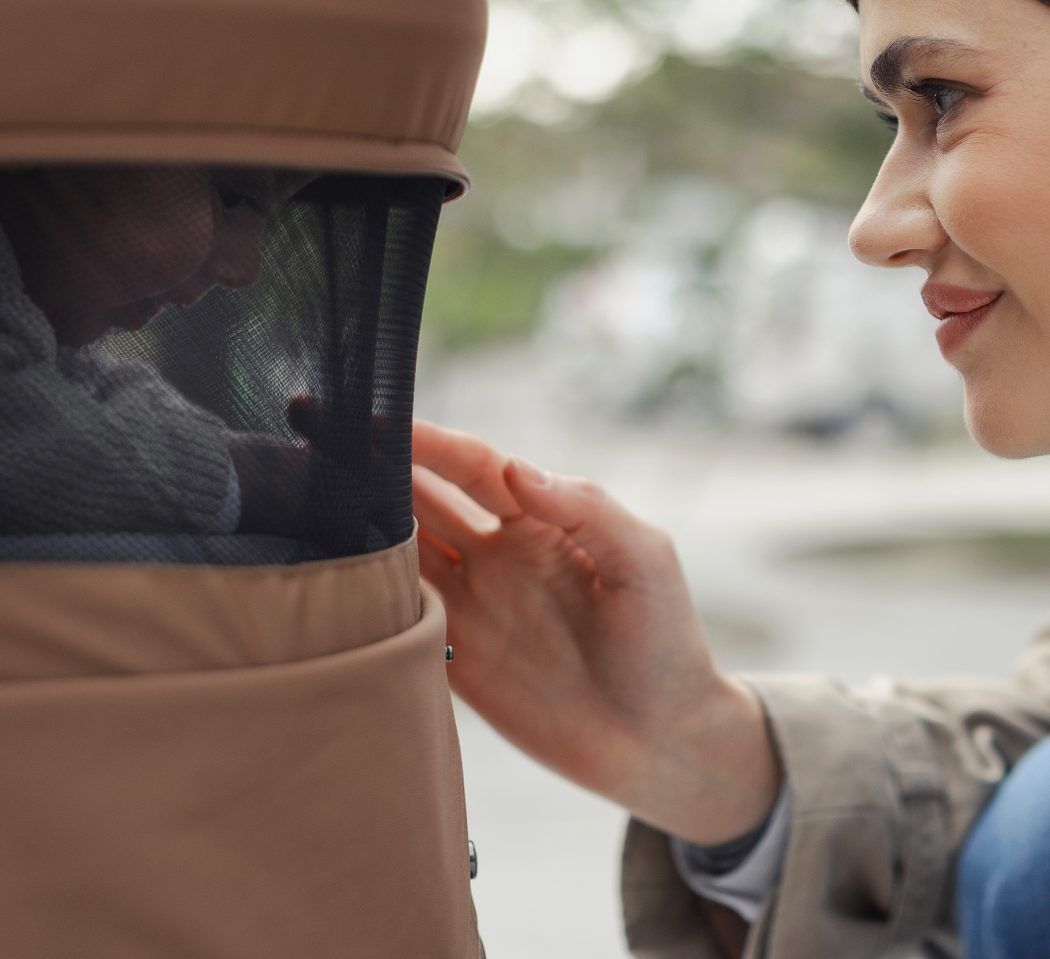 mutter betrachtet baby durch netzfenster in babywanne venicci claro leichter kinderwagen