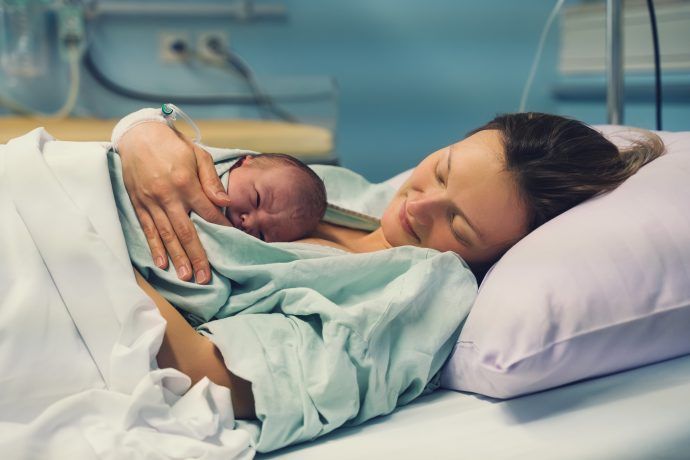 dammschnitt geburt mutter und neugeborenes baby liegen im kreißsaal krankenhaus