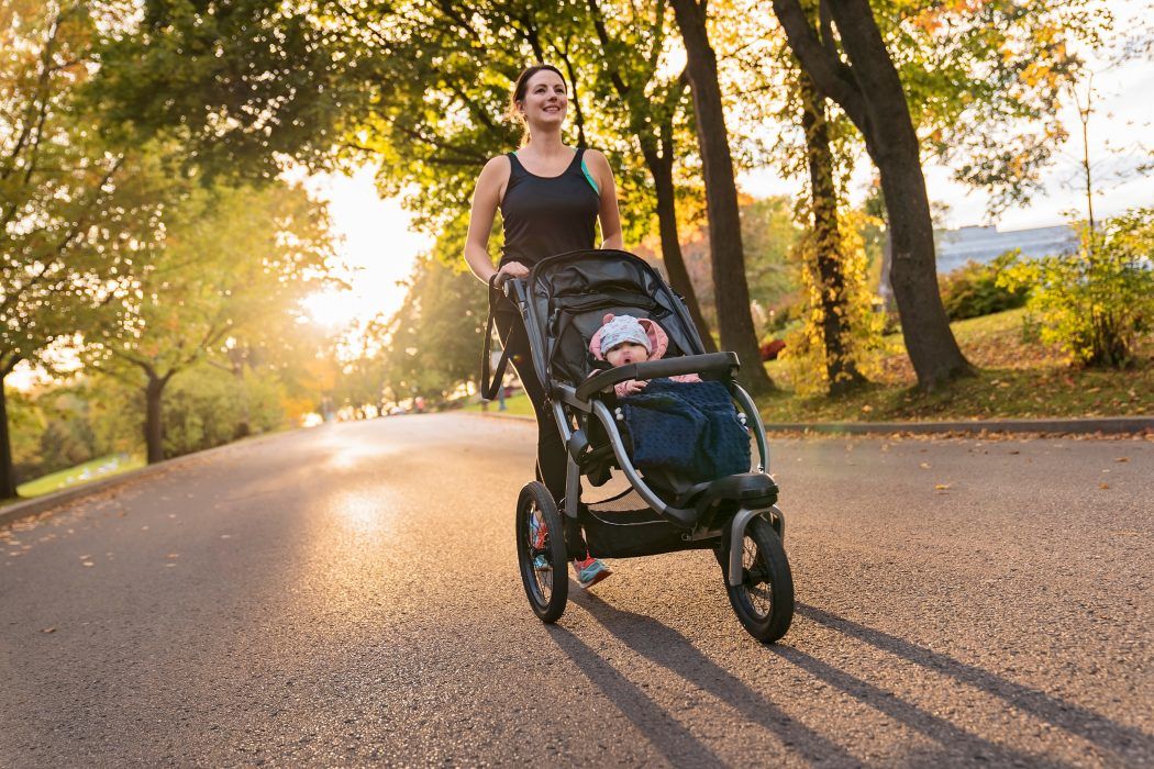 mutter beim joggen mit kinderwagen baby gekleidet mit jacke decke mütze