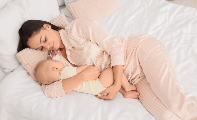 mutter mit dammriss bei geburt liegt im bett mit baby im arm