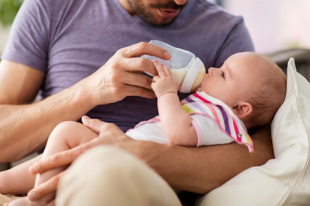 vater füttert baby mit flasche, pre milch wie lange